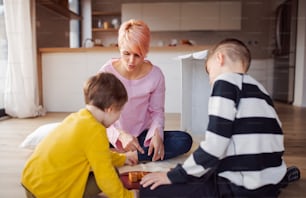 A young mother with two children playing board games on the floor.