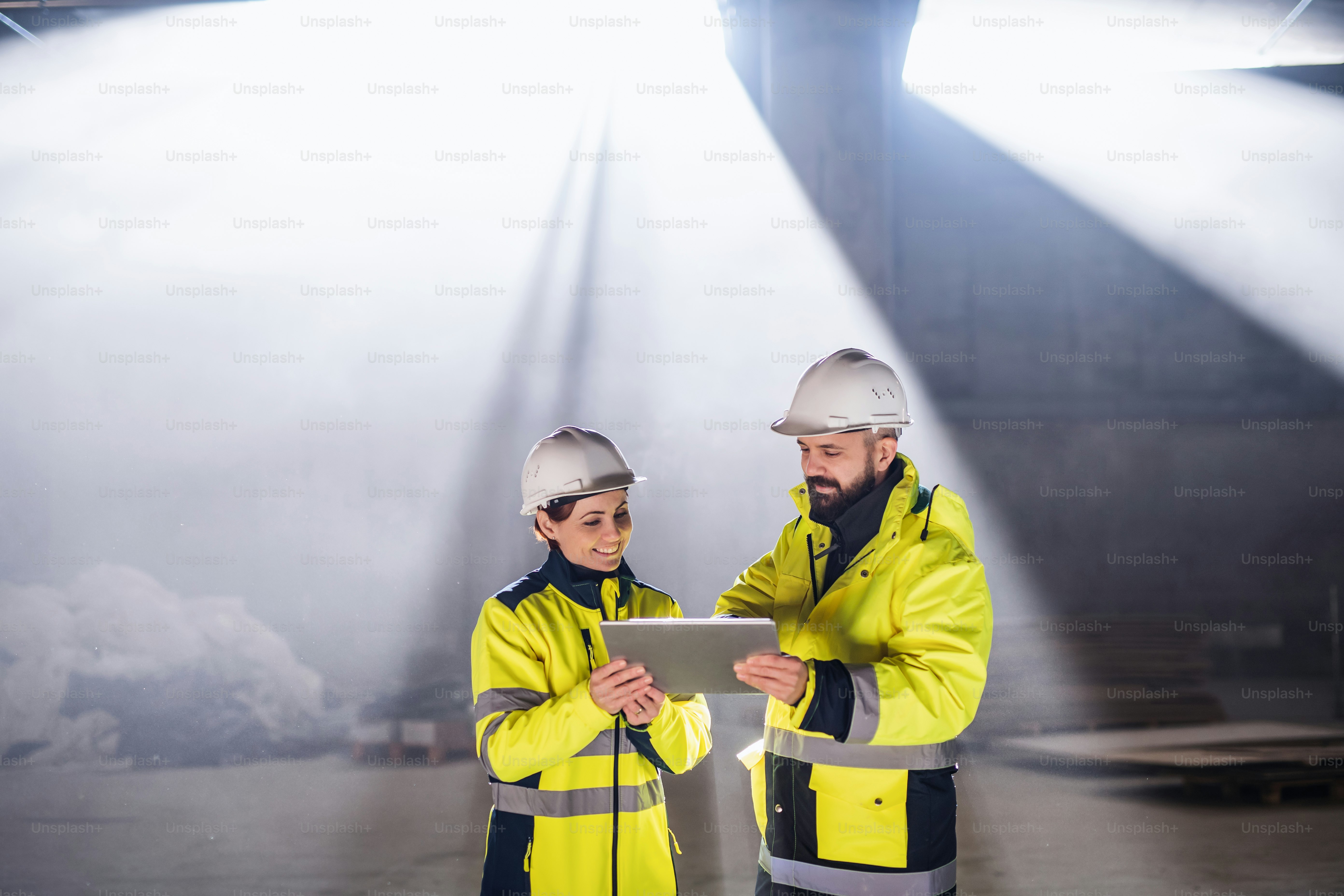 Engenheiros em pé e conversando ao ar livre no canteiro de obras, segurando tablet.
