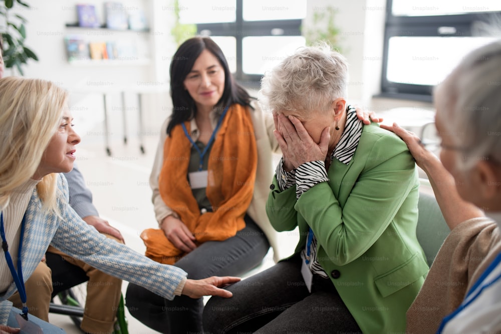 치료 세션 동안 서클에 앉아 우울한 여성을 위로하는 노인 그룹.