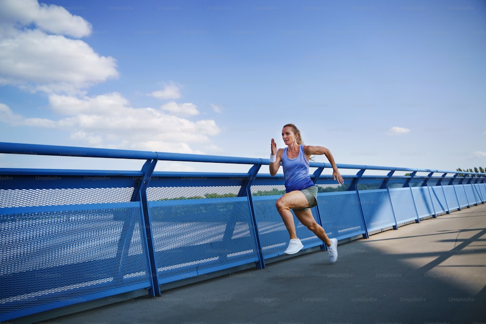 A mid adult woman running outdoors in city, healthy lifestyle concept.