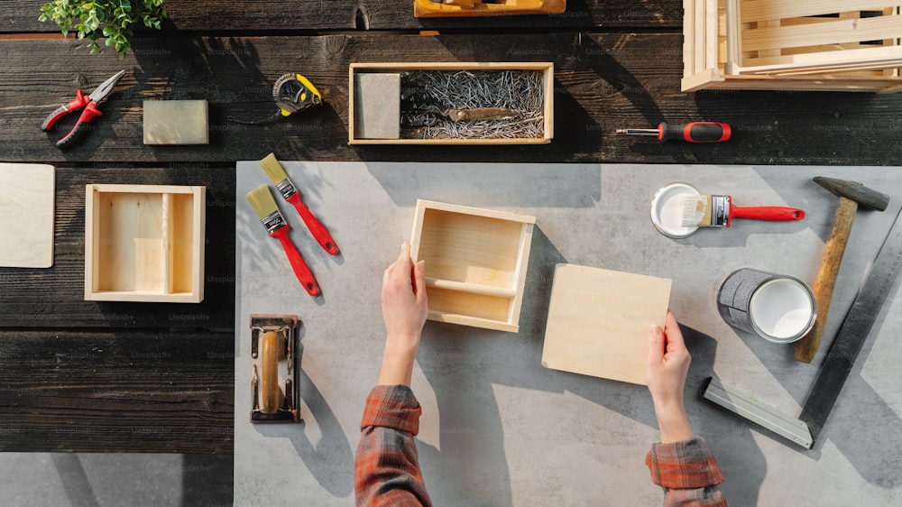 A top view of unrecognizable woman making wooden boxes, small business and desktop concept.