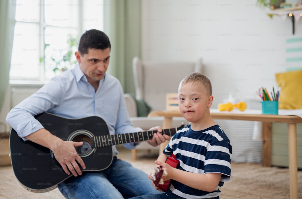 A cheerful down syndrome boy with father playing musical instruments, laughing.