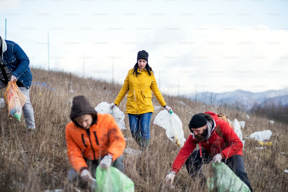 Group of activists picking up litter in nature, environmental pollution and plogging concept.