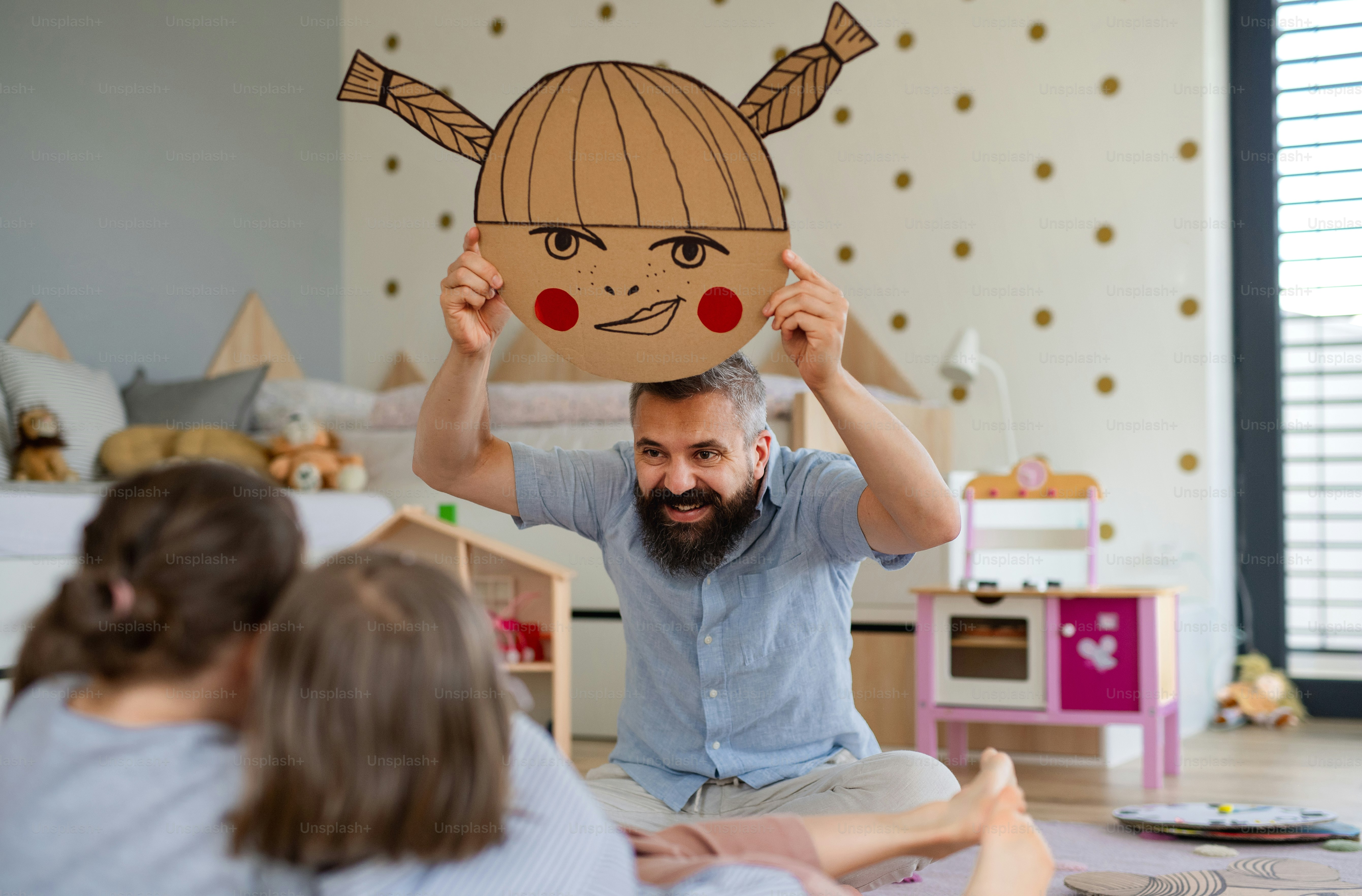 A father with three daughters indoors at home, playing on floor