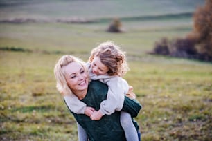 Portrait of small girl with mother on a walk in autumn nature, having fun.