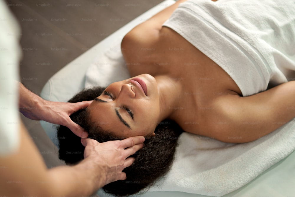 Una vista dall'alto di una giovane donna che fa un massaggio rilassante alla testa presso la spa.