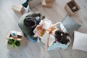 Top view of young couple with hamburgers and boxes moving in new flat, new home and relocation concept.