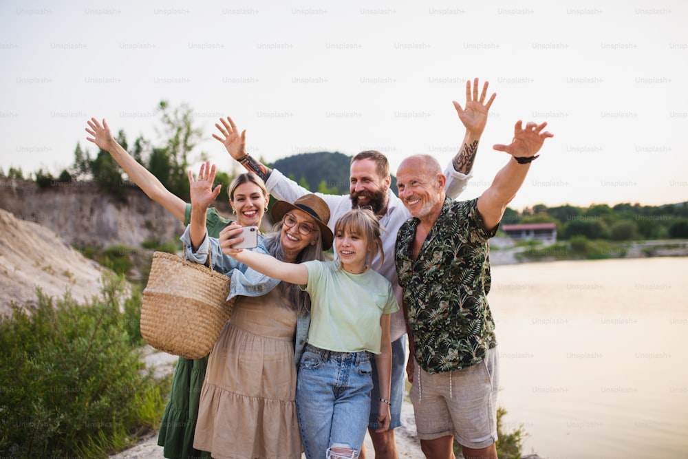 Une famille multigénérationnelle heureuse en randonnée pendant les vacances d’été, en prenant un selfie.