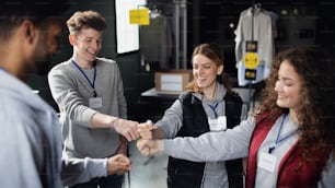 A group of volunteers at work in community charity donation center, fist bump.