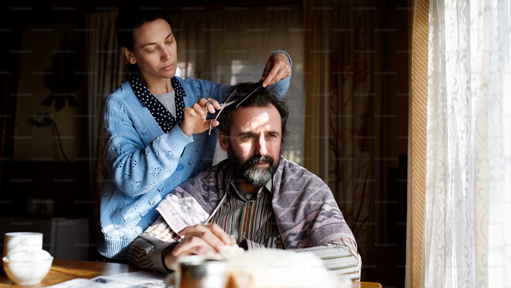Ein Porträt einer armen Frau, die Ehemännern zu Hause die Haare schneidet, Armutskonzept.