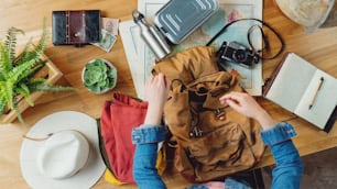 Top view of young woman packing backpack for vacation trip holiday, desktop travel concept.