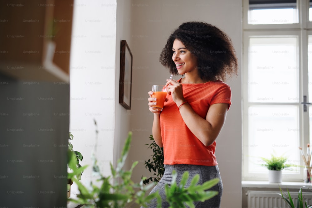 Happy young woman with drink indoors at home, doing exercise. Sport concept.