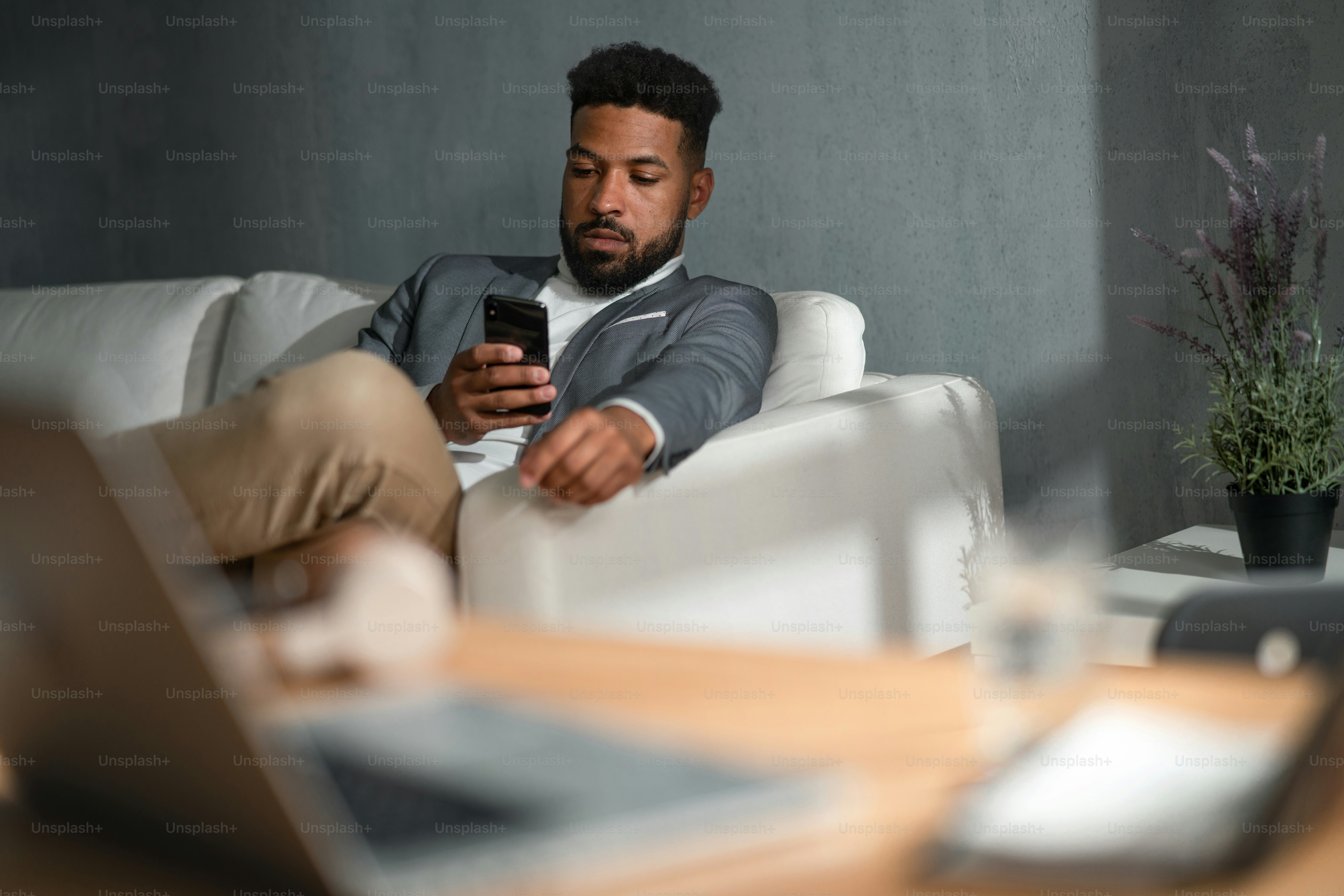 Un jeune homme d'affaires afro-américain avec un smartphone assis sur un  canapé à l'intérieur d'un bureau photo – Image de Affaire sur Unsplash, image size:3000x2001