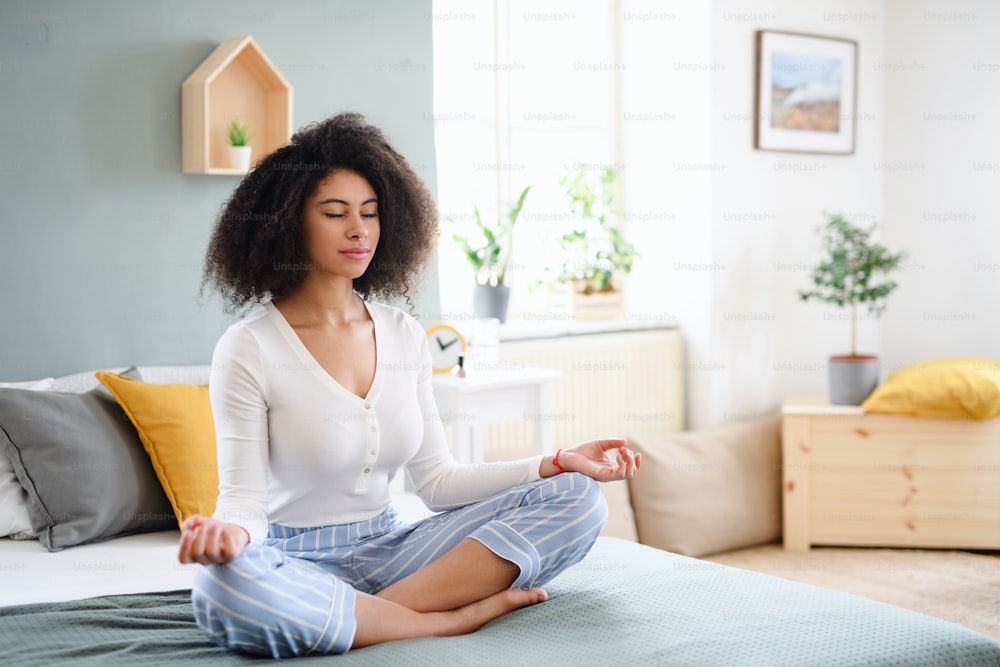 Portrait of relaxed young woman indoors at home, doing yoga exercise on bed.