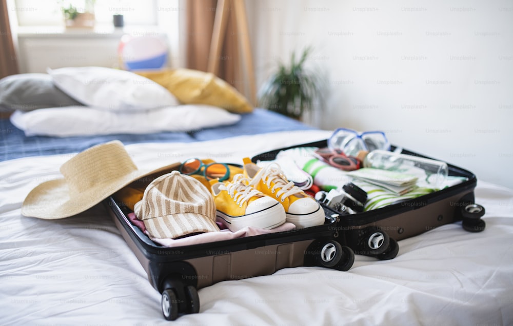Une valise ouverte emballée pour les vacances sur le lit à la maison, concept de coronavirus.