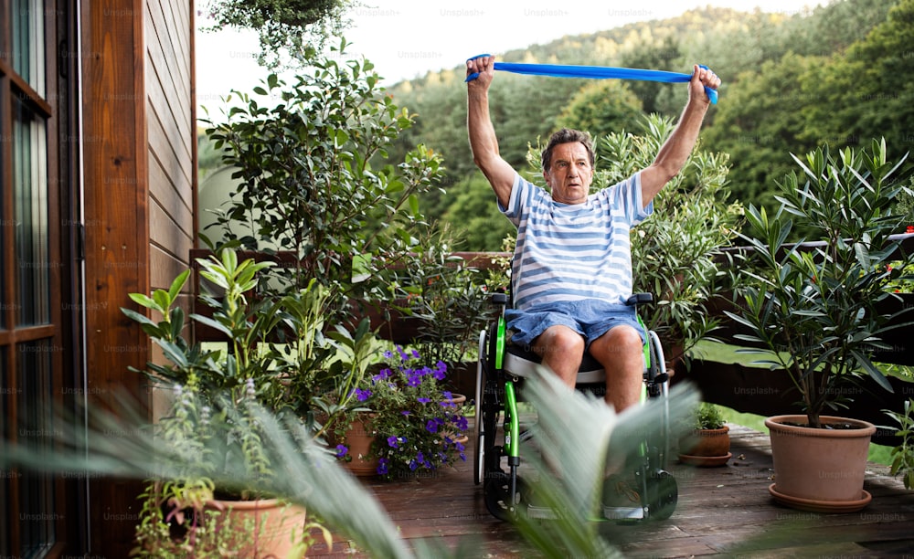 Ein älterer Mann im Rollstuhl, der auf der Terrasse Sport treibt.