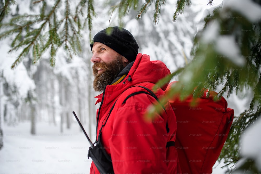 Paramedic from mountain rescue service walking and talking outdoors in winter in forest.
