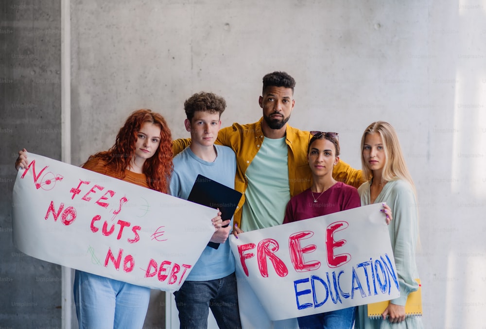 University students activists protesting indoors at school, looking at camera, fighting for free education.