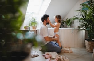 Vista lateral de un padre maduro con una hija pequeña en el interior de la casa, preparándose para un baño.