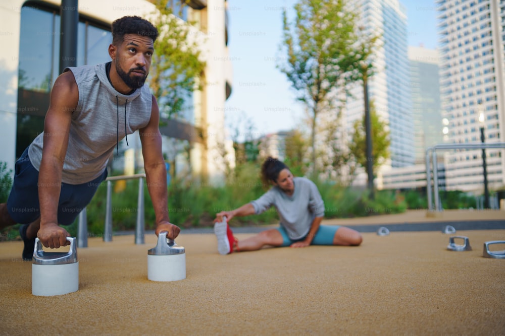 A young man doing push-ups outdoors in city, workout exercise and healthy lifestyle concept.