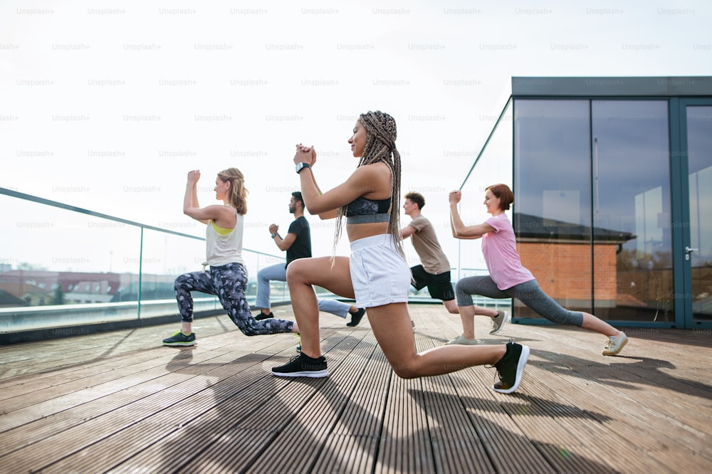 Eine Gruppe junger Menschen, die sich im Freien auf der Terrasse bewegen, Sport treiben und ein gesundes Lebensstilkonzept entwickeln.