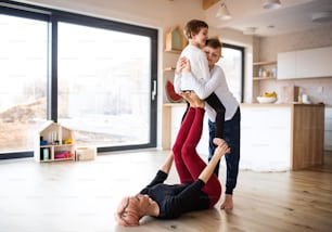 A happy young woman with two children playing on the floor, having fun.