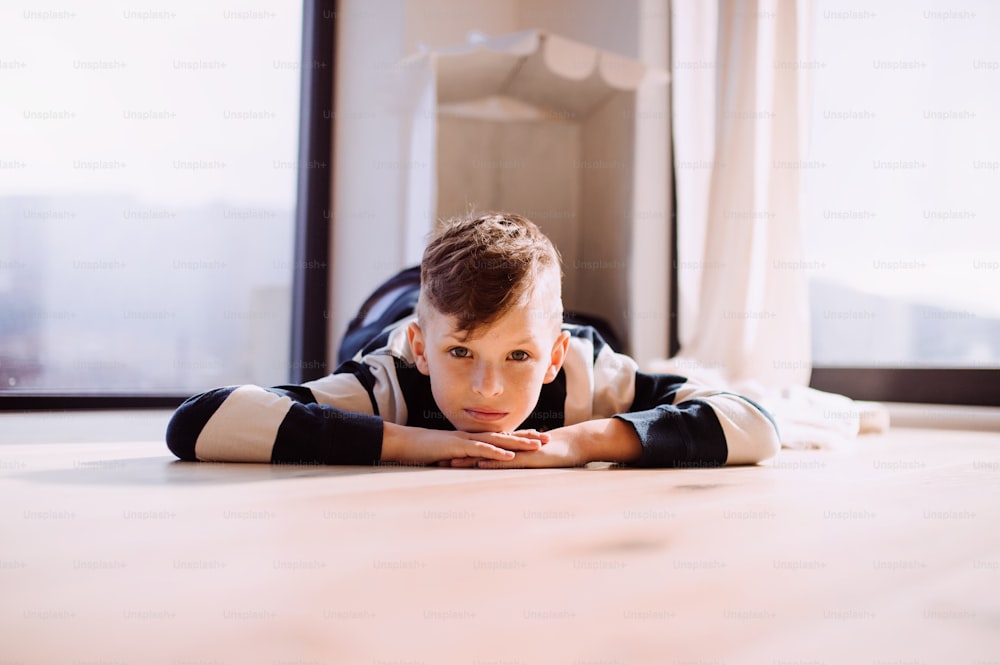 A happy small boy lying indoors on the floor at home. Copy space.