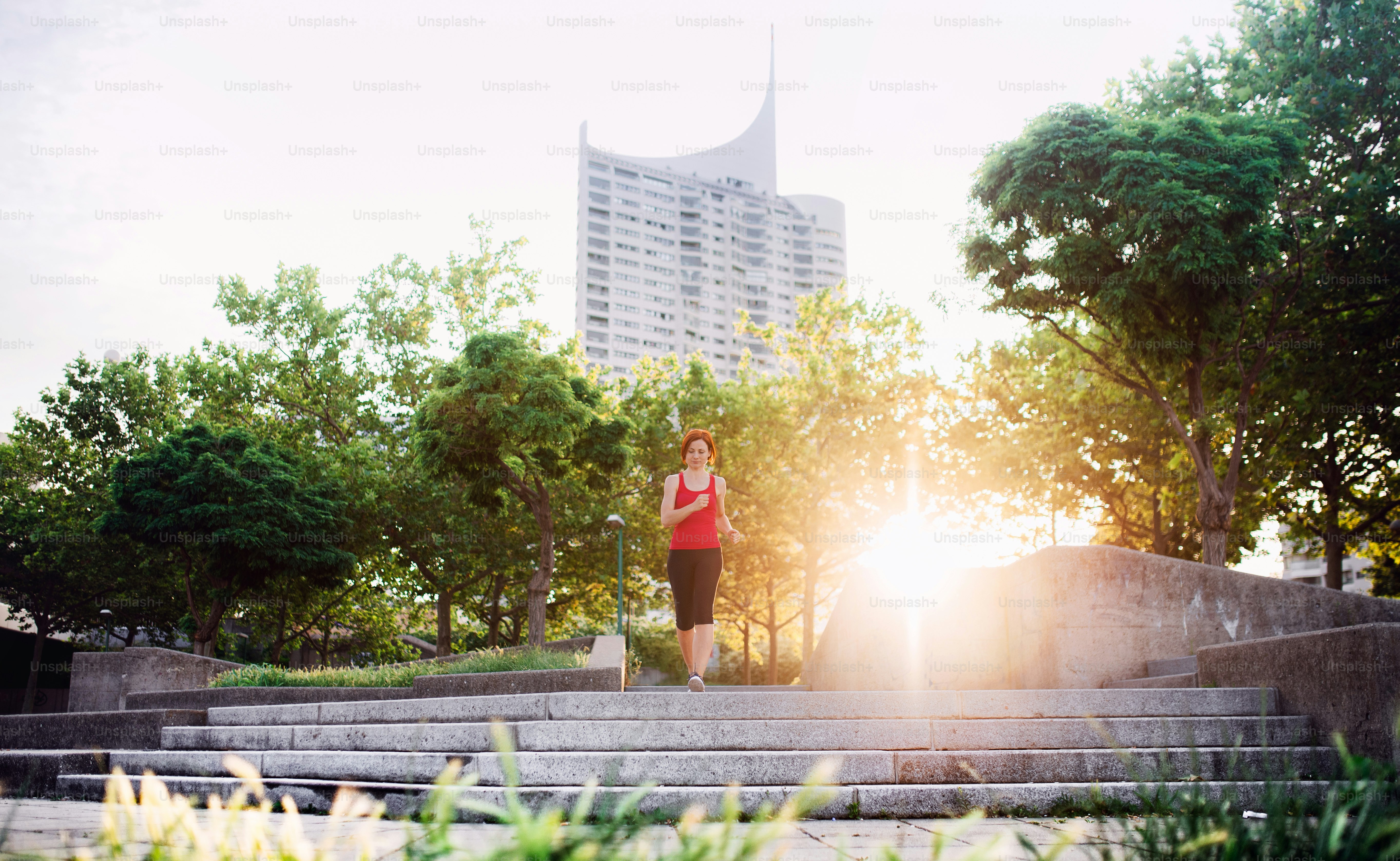 Young woman runner jogging outdoors in city at sunrise early in the morning.