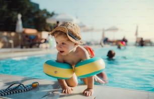 Ein fröhlicher kleiner Kleinkind mit Armbinden und seine Mutter, die in den Sommerferien im Wasser schwimmt.