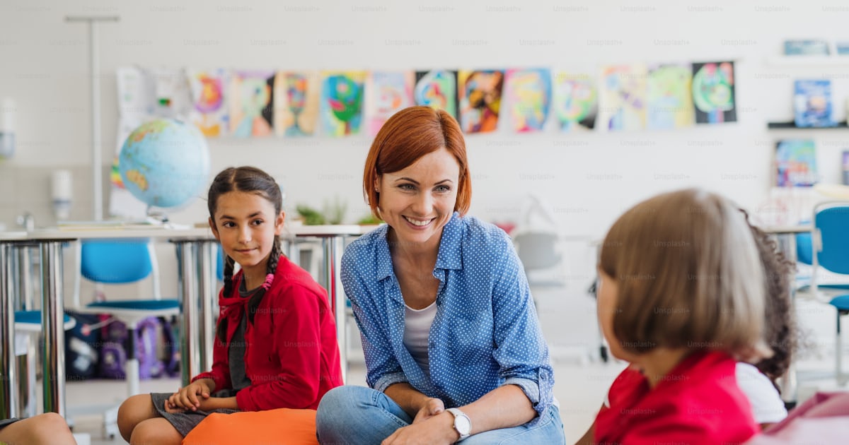 A group of small school kids with teacher sitting on bean bags in class A group of small school kids with teacher sitting on bean bags in class