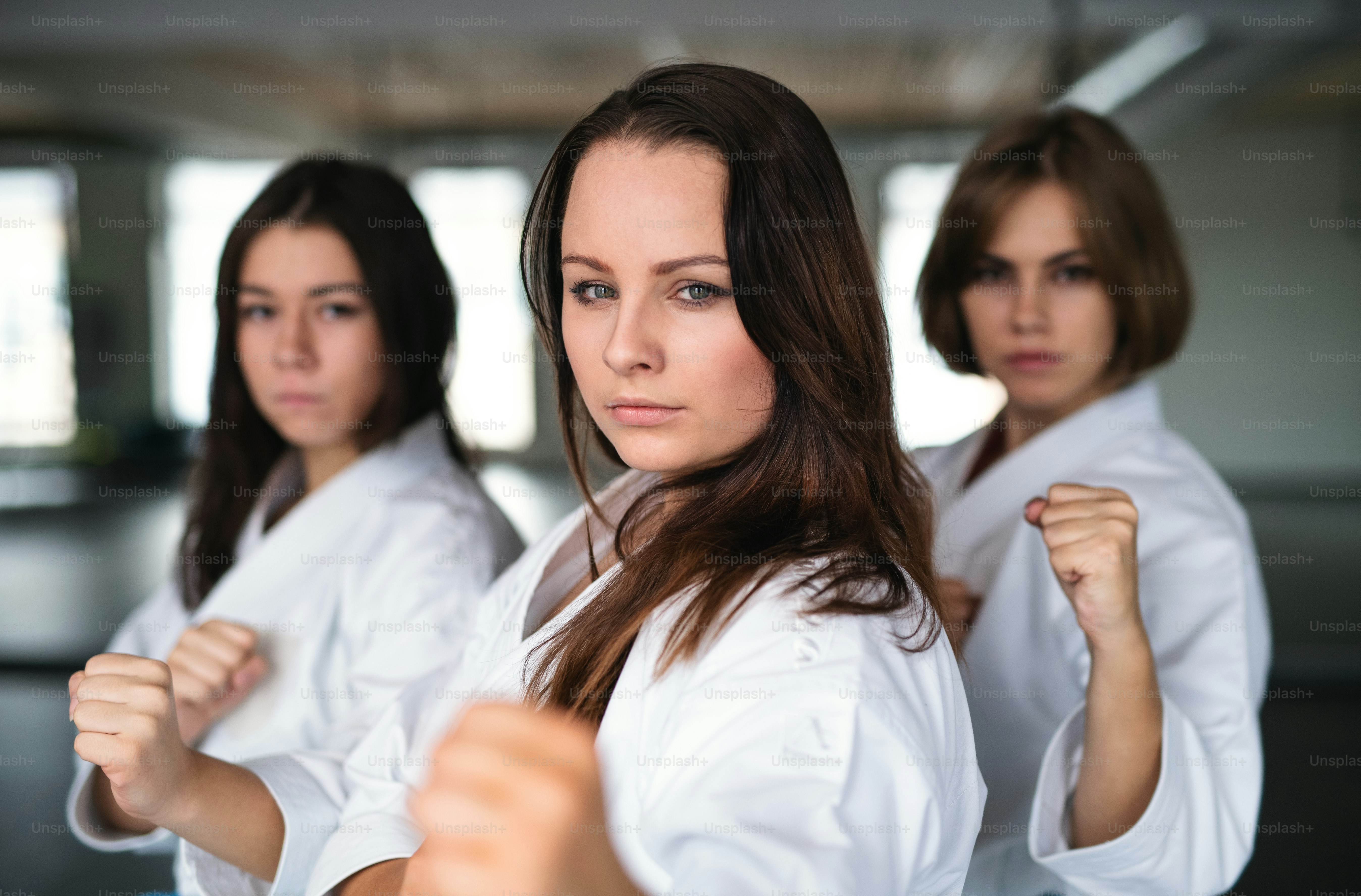 Un groupe de jeunes femmes pratiquant le karaté à l’intérieur dans un gymnase