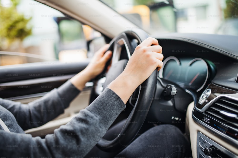 Une section médiane des bras d’une jeune conductrice assise dans une voiture, conduisant.