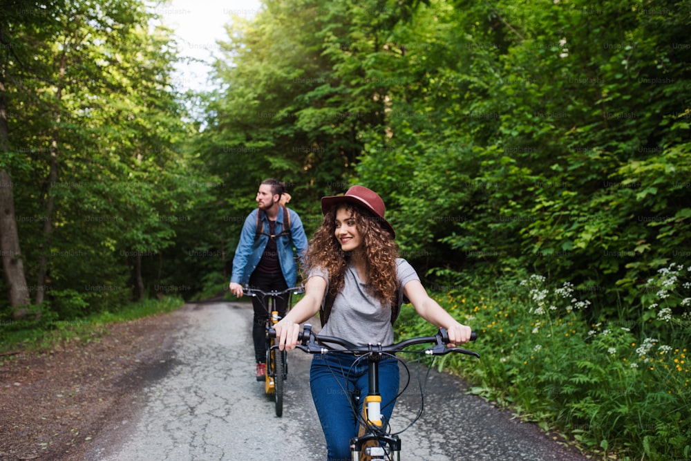 Young tourist couple travellers with backpacks and electric scooters in nature.