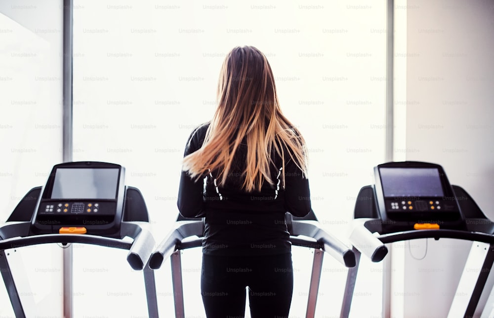 A rear view of a beautiful young girl or woman doing cardio workout in a gym.