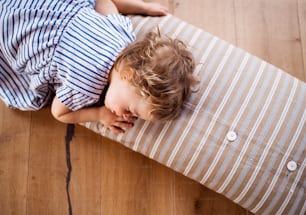 A top view of a toddler girl lying on the floor indoors at home, sleeping.