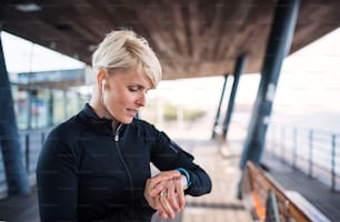 A portrait of young sportswoman with smartwatch outdoors, self-tracking. Copy space.