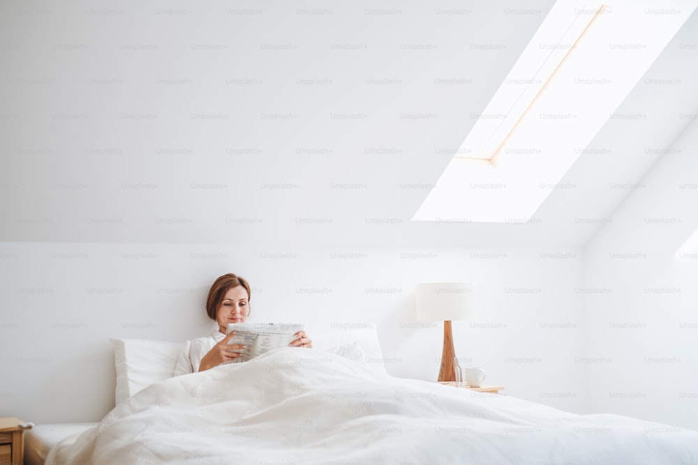 Una rutina matutina de una mujer joven leyendo periódicos en la cama en un dormitorio.
