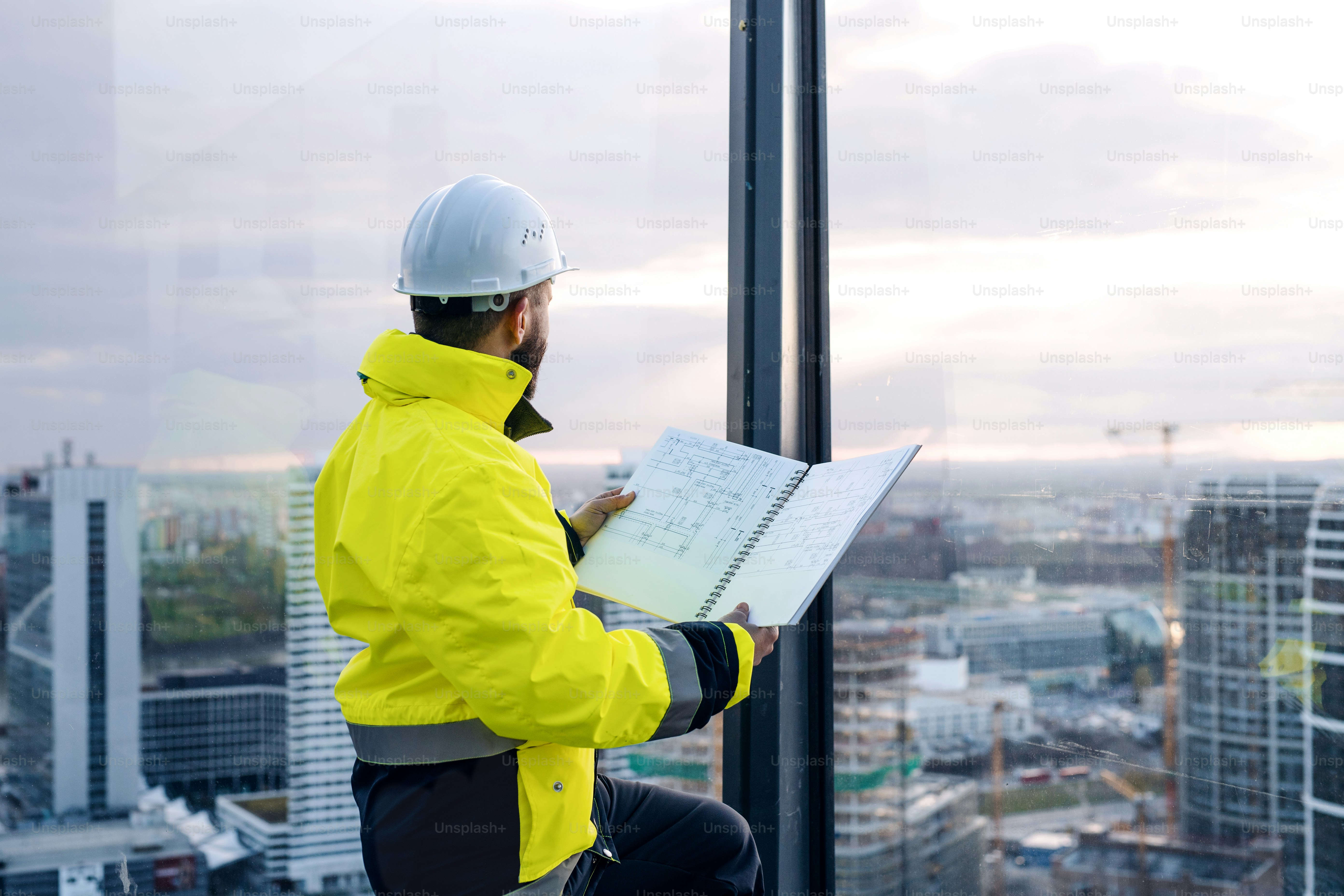 Ingeniero hombre maduro de pie en el sitio de construcción, sosteniendo planos.