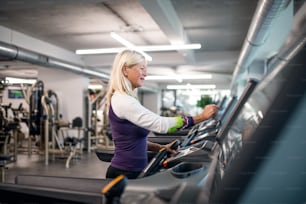 A happy senior woman in gym doing cardio work out exercise.