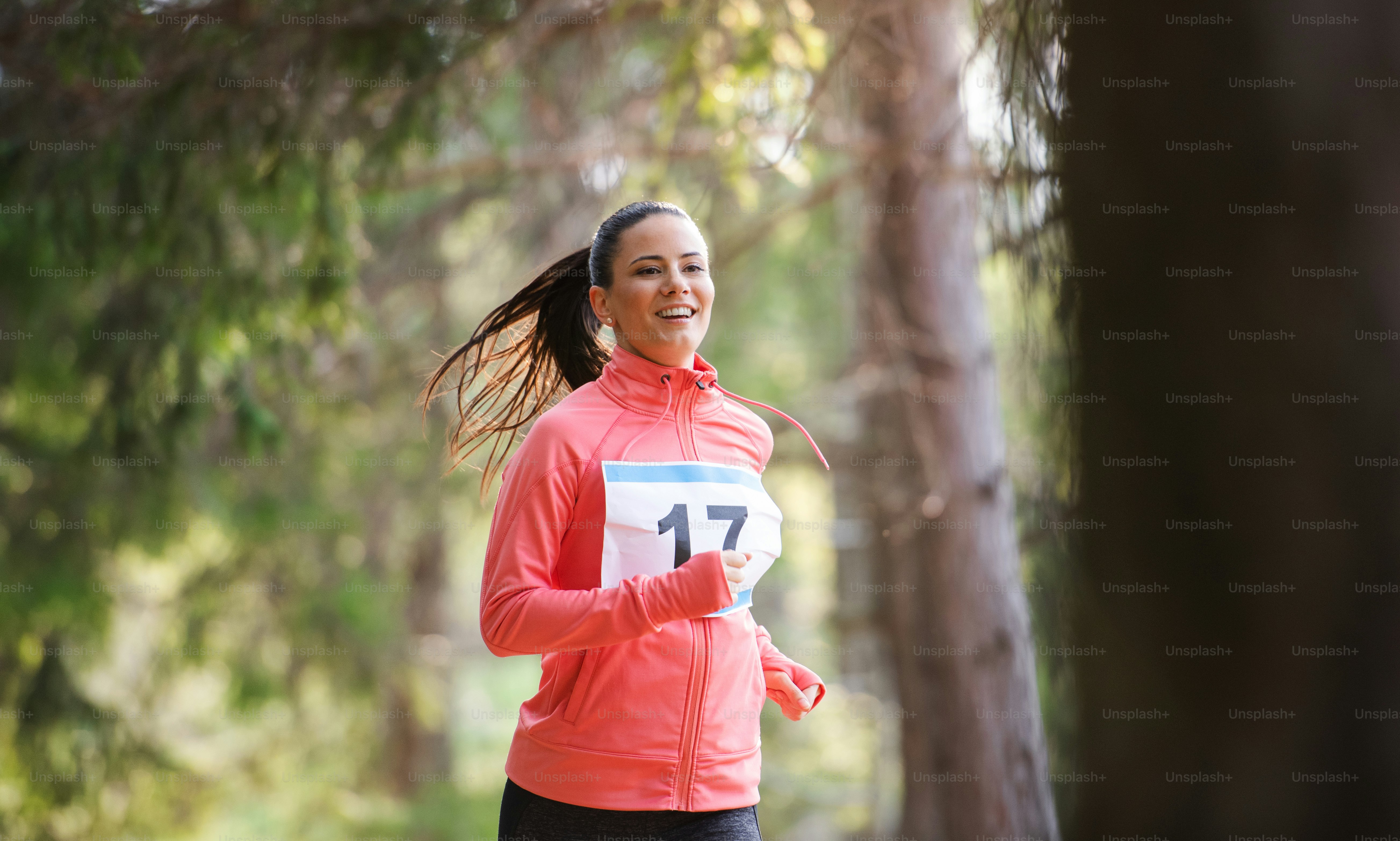 Uma visão frontal da jovem mulher correndo uma competição de corrida na natureza. Espaço de cópia.