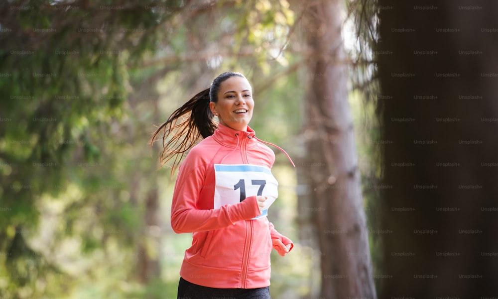A front view of young woman running a race competition in nature. Copy space.