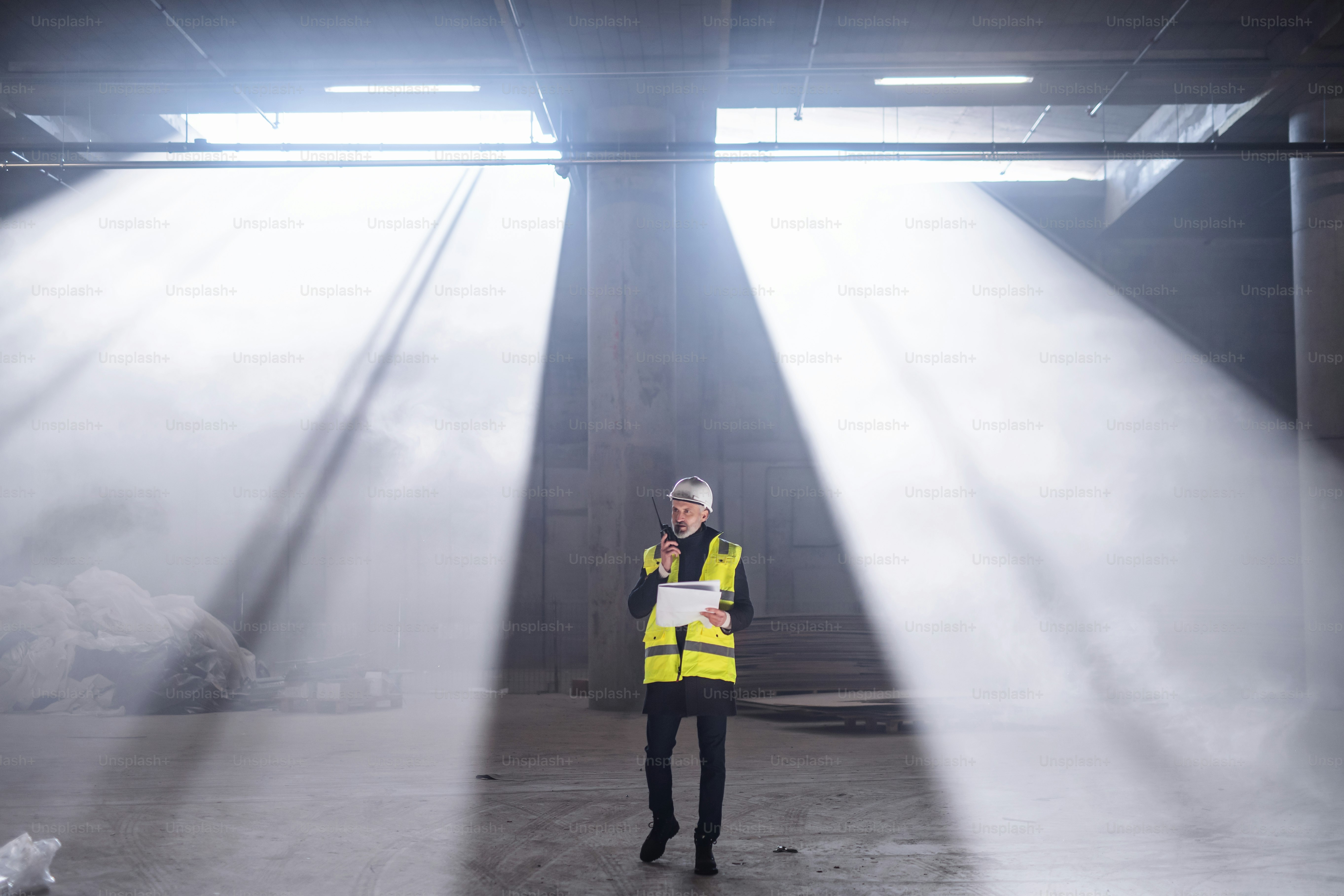 Ingeniero de hombre usando walkie talkie en interiores en el sitio de construcción.