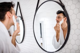 A young man shaving in the bathroom in the morning, a daily routine.