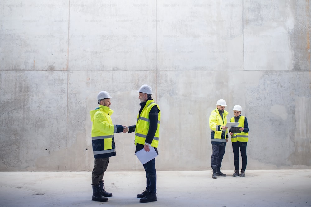 Un groupe d’ingénieurs debout sur le chantier de construction, se serrant la main. Espace de copie.