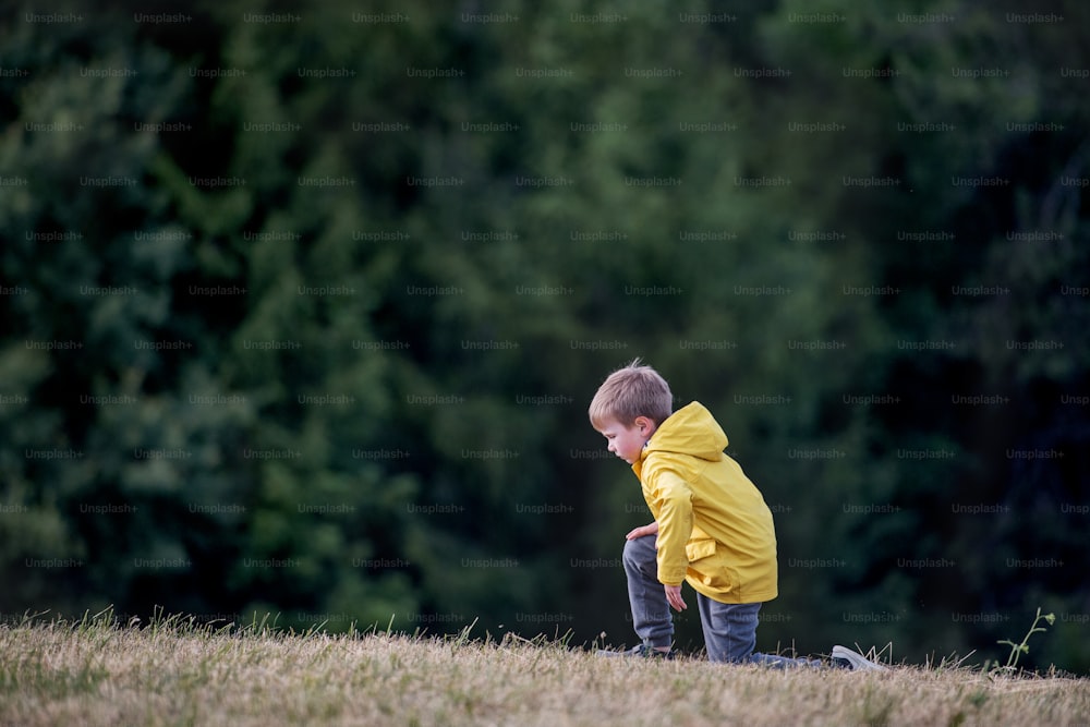 A side view of school child standing on field trip in nature, resting.