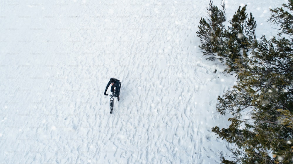 Veduta aerea del mountain biker che cavalca sulla neve nella foresta all'aperto in inverno. Copia spazio.