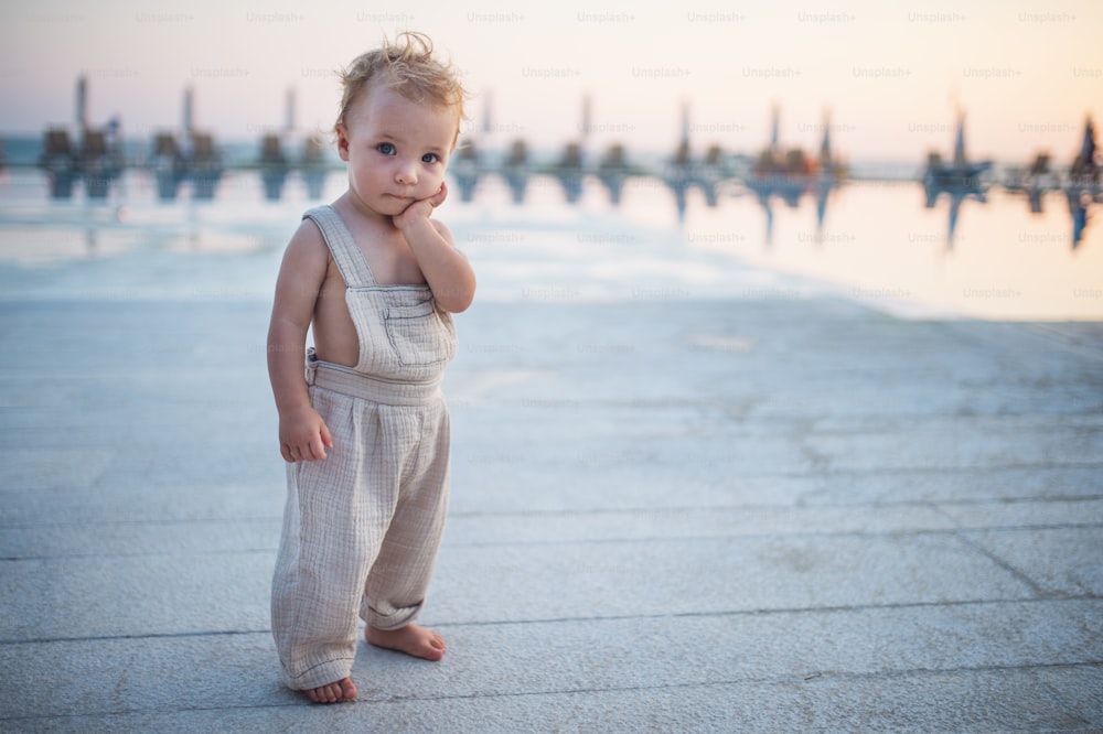 A cute small toddler girl standing on beach on summer holiday. Copy space.