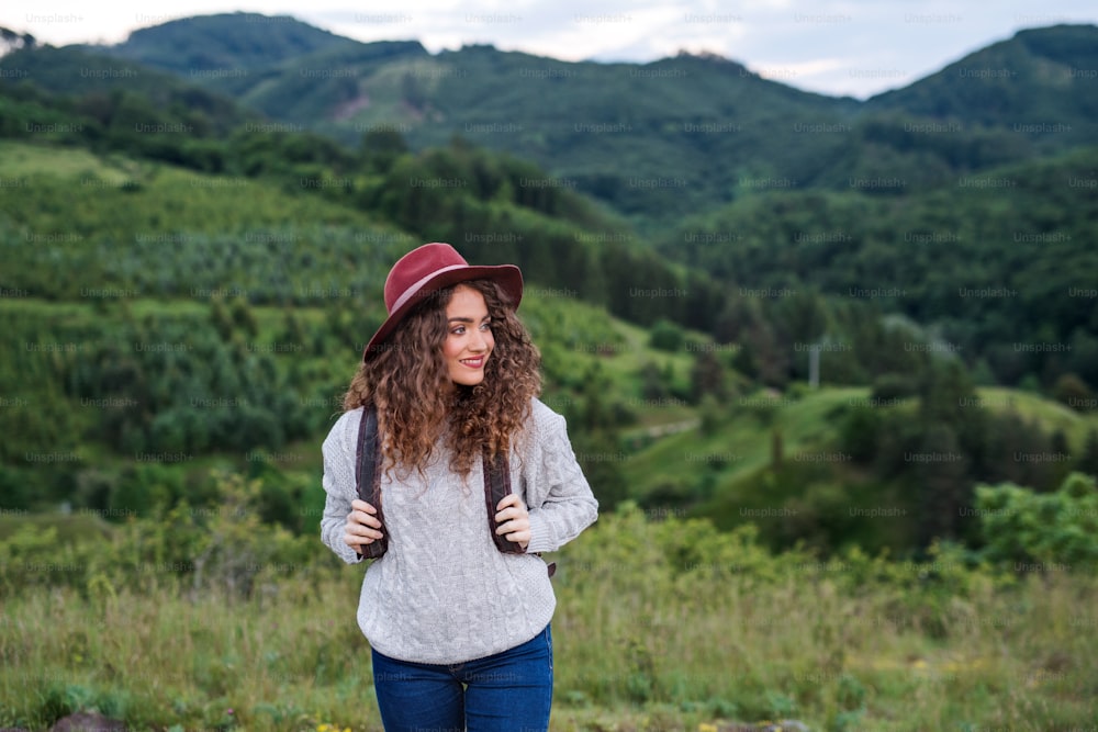 Vista frontale della giovane turista viaggiatrice con zaino che cammina nella natura.