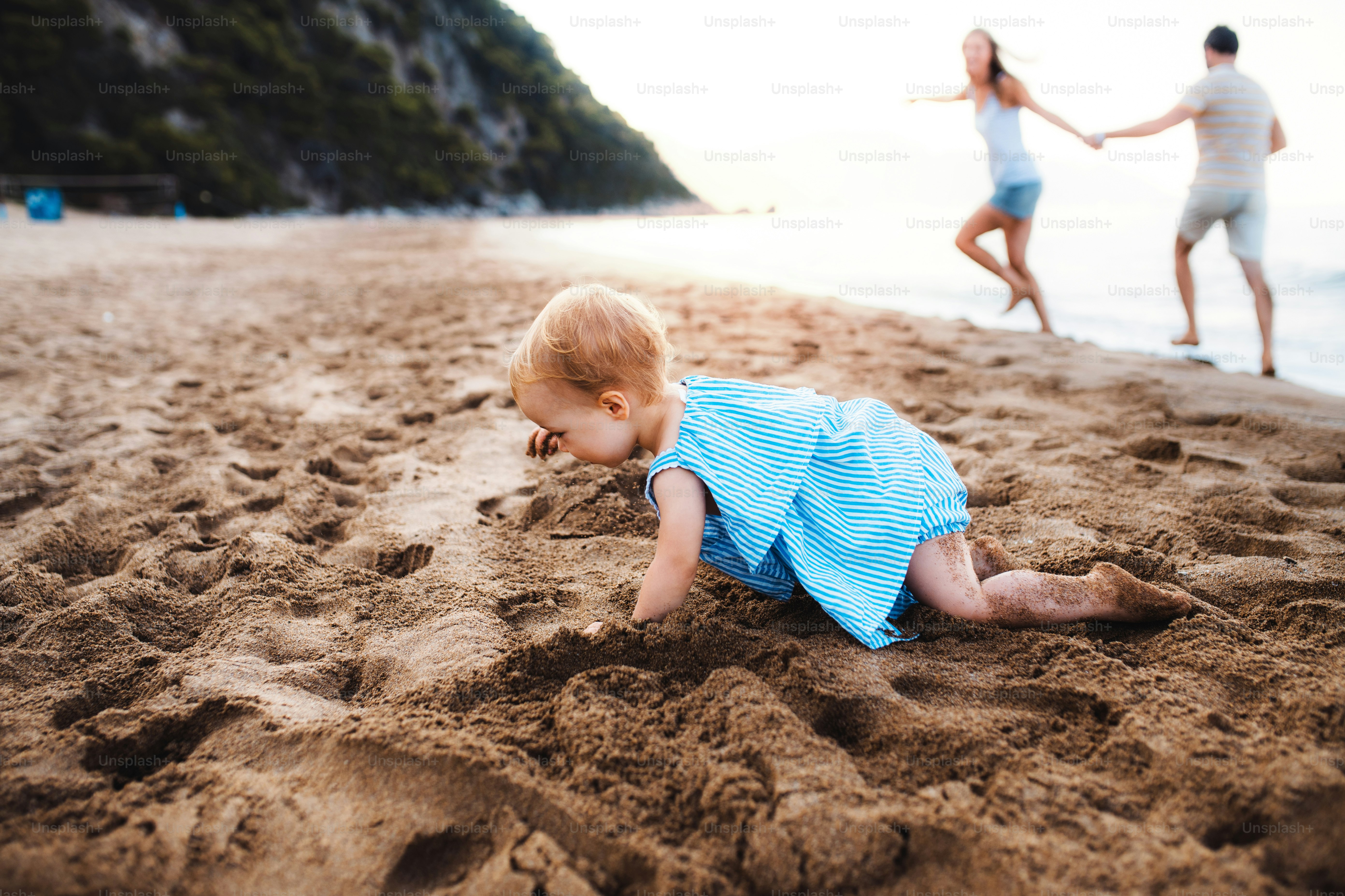 Ein kleines Kleinkind, das in den Sommerferien am Strand im Sand spielt. Speicherplatz kopieren.
