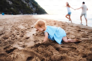 Uma menina pequena que brinca na areia na praia nas férias de verão. Espaço de cópia.